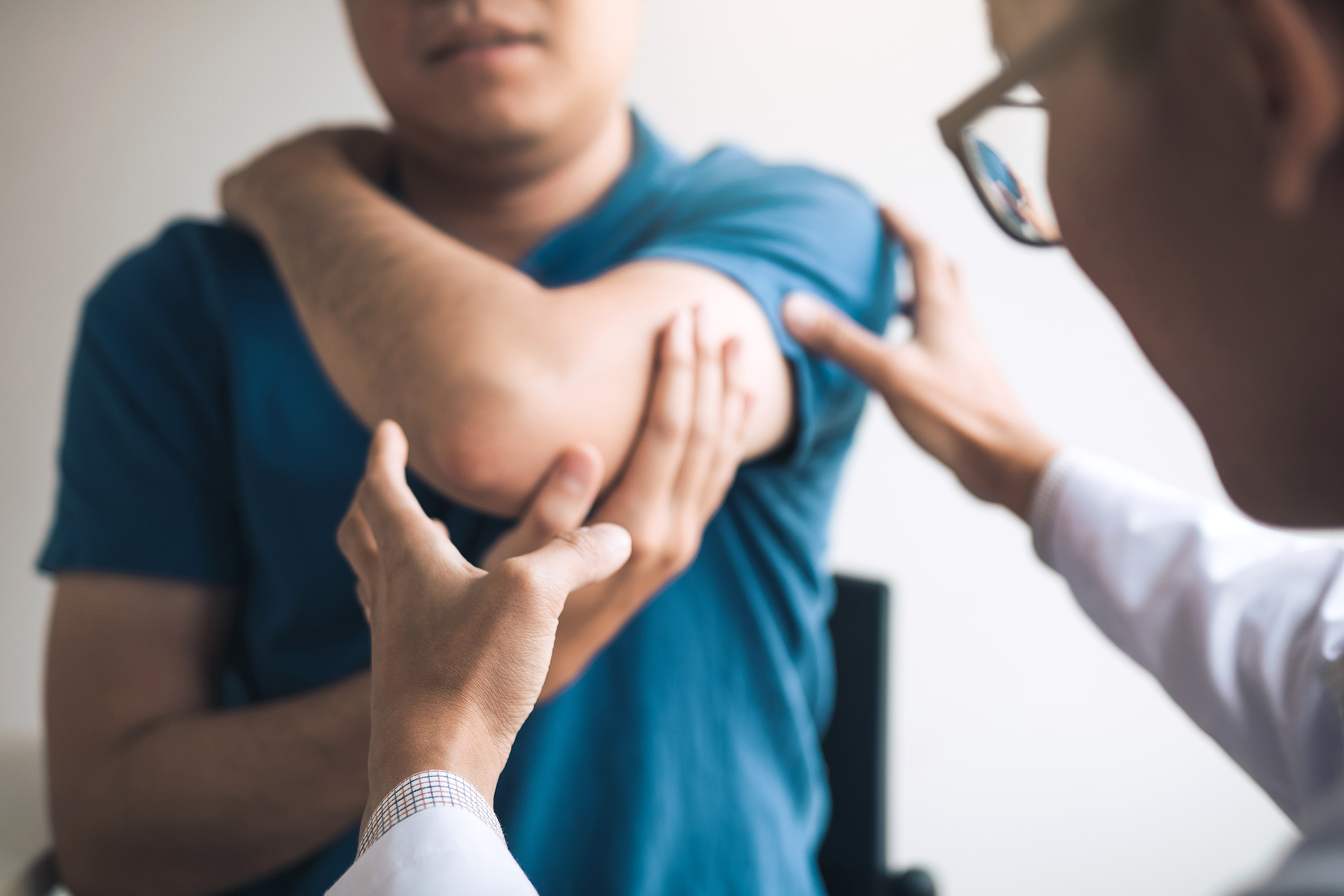 A man rubbing his upper arm while speaking with his doctor