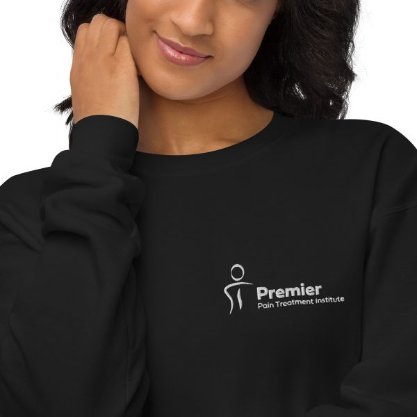 A female wearing a black long sleeve sweater with the Premier Pain Treatment Institute logo on the front