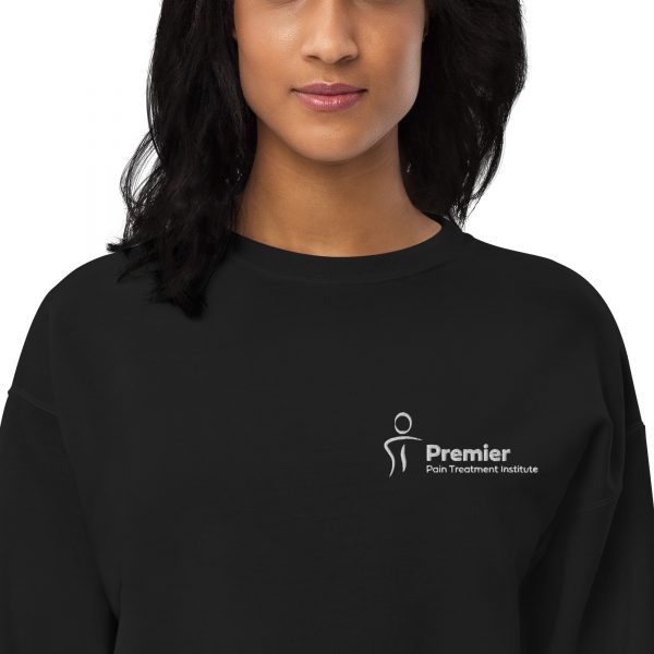 A female wearing a black long sleeve sweater with the Premier Pain Treatment Institute logo on the front