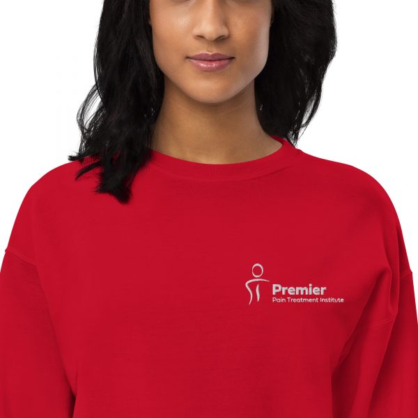 A female wearing a red long sleeve sweater with the Premier Pain Treatment Institute logo on the front