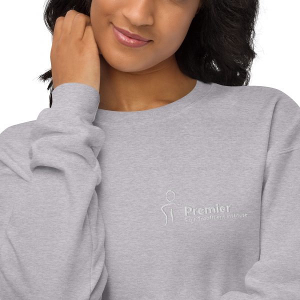 A female wearing a grey long sleeve sweater with the Premier Pain Treatment Institute logo on the front